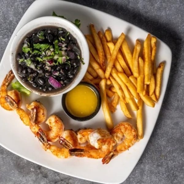 Grilled shrimp, french fries, black beans with cilantro and onions, and a side of butter.